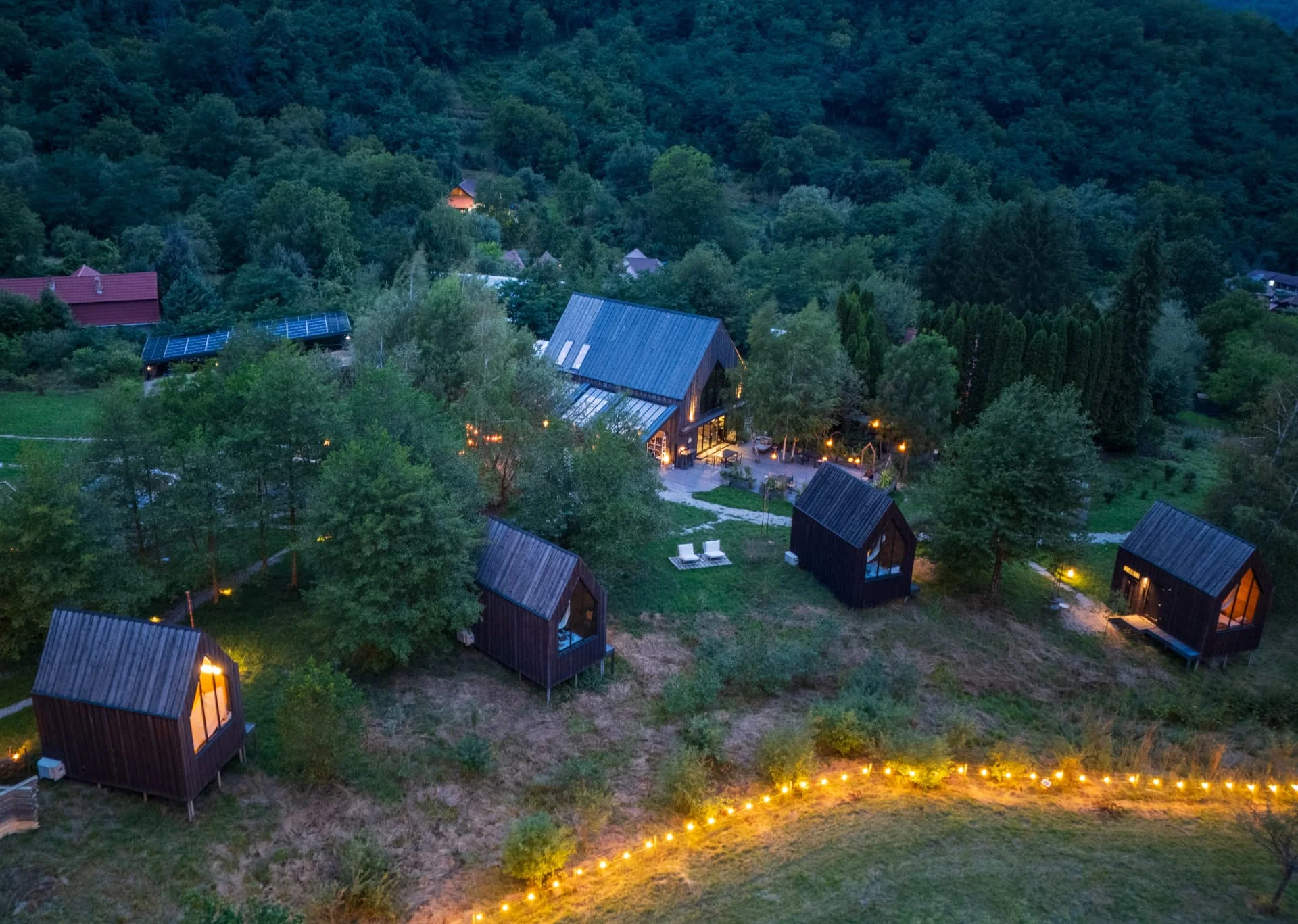 Satul Portal Village noaptea, între pădure și lumini calde