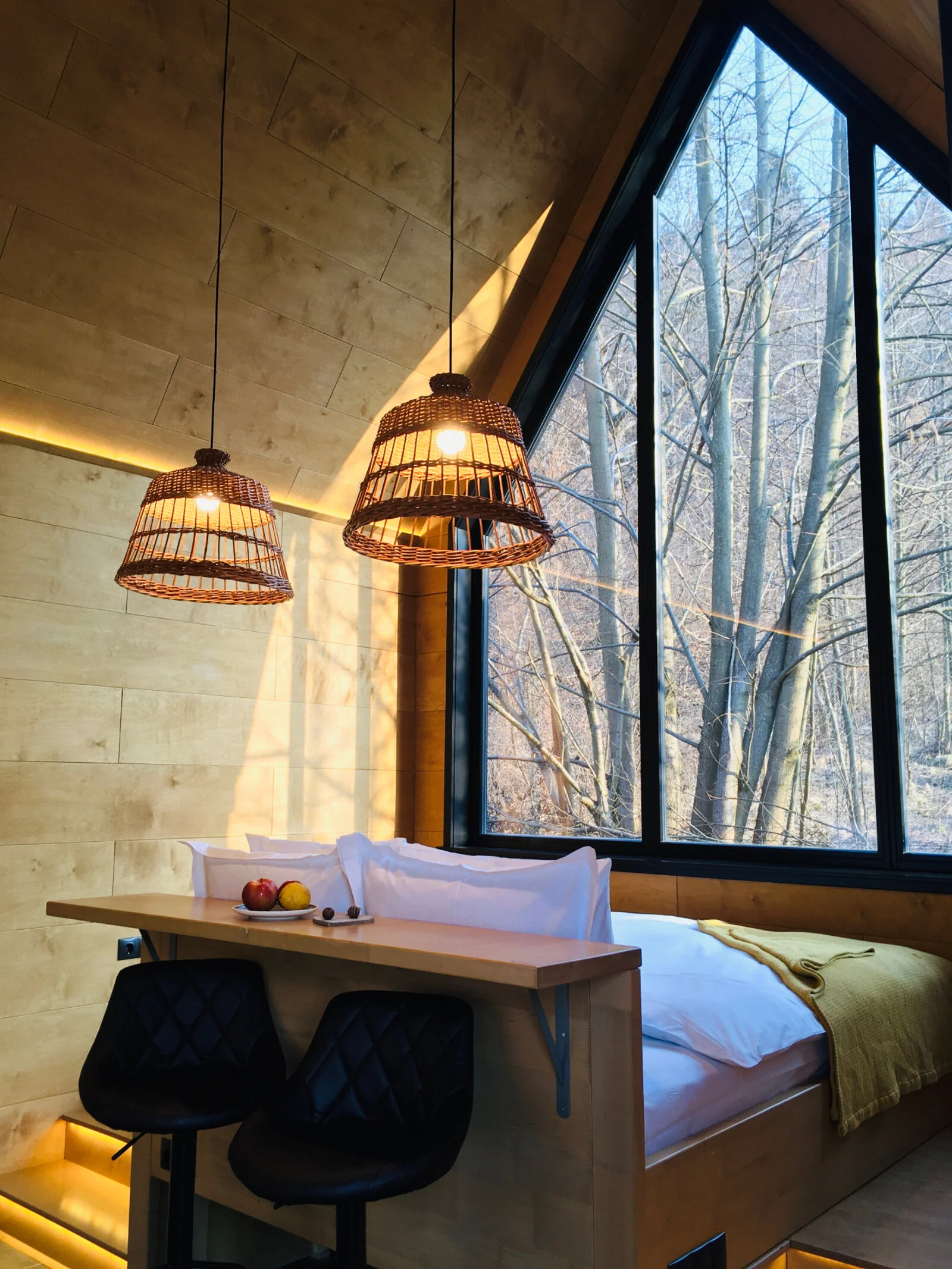 Interior de bungalou cu pat și fereastră spre pădure